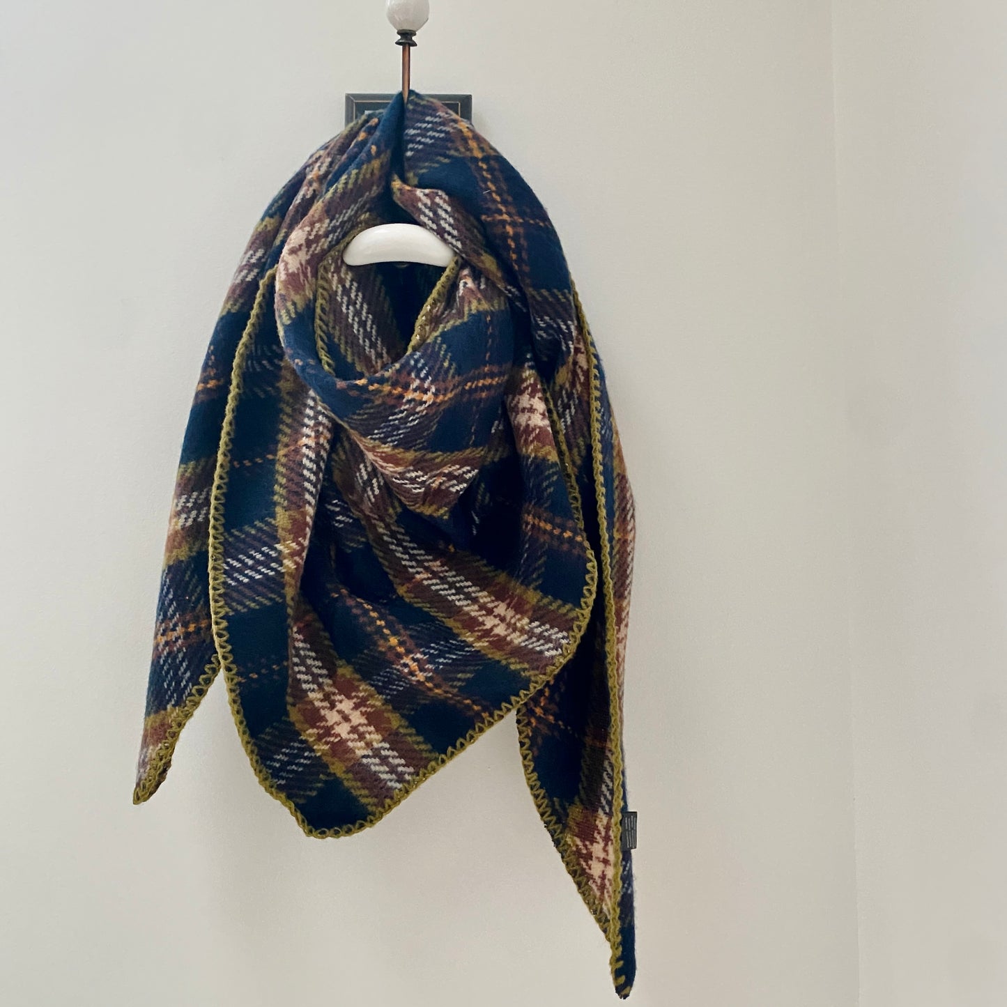      Navy tartan pattern thick scarf     Triangular shaped      Blanket stitched edge detail in khaki     Super soft feel     80% Acrylic 20% Wool     Measures 37" (at longest width point) x 37" (at honest depth point)     Also available in Red